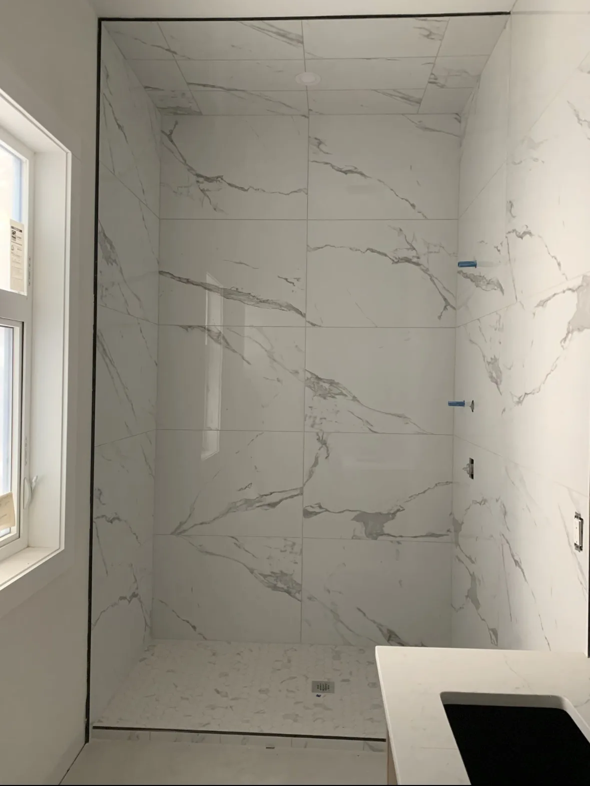 Calgary large-format marble shower install — full white marble porcelain with hexagon mosaic shower floor