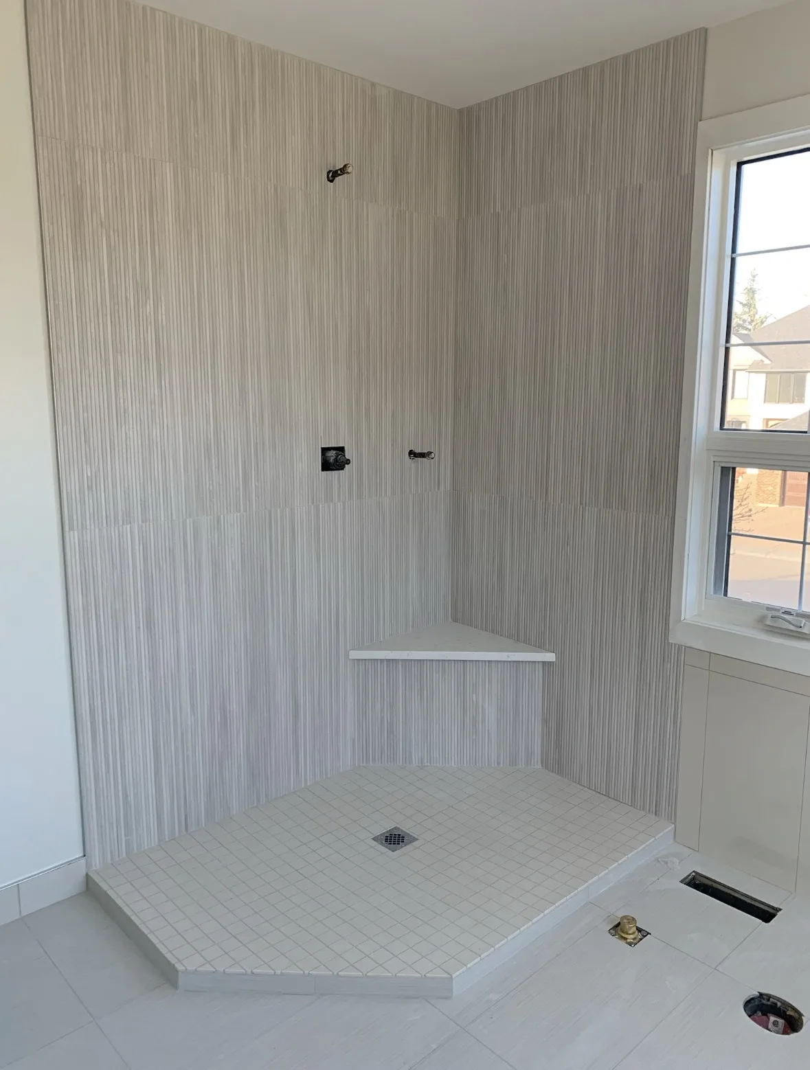 Calgary walk-in shower tile install — vertical linear linen-look tile with corner bench and window