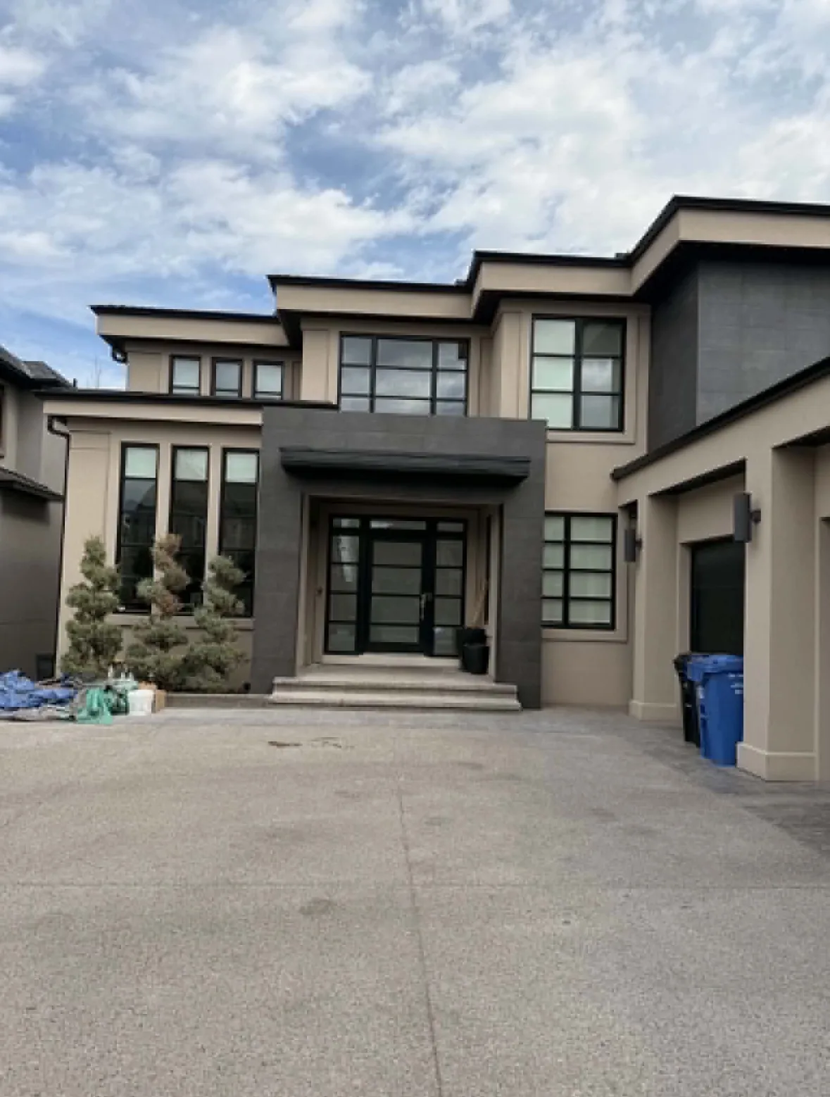 Calgary luxury home exterior entryway after porcelain tile cladding installed — dark large-format tile portico, clean modern finish