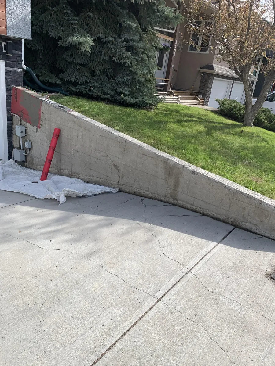Calgary retaining wall parging before — chipped corners and surface damage