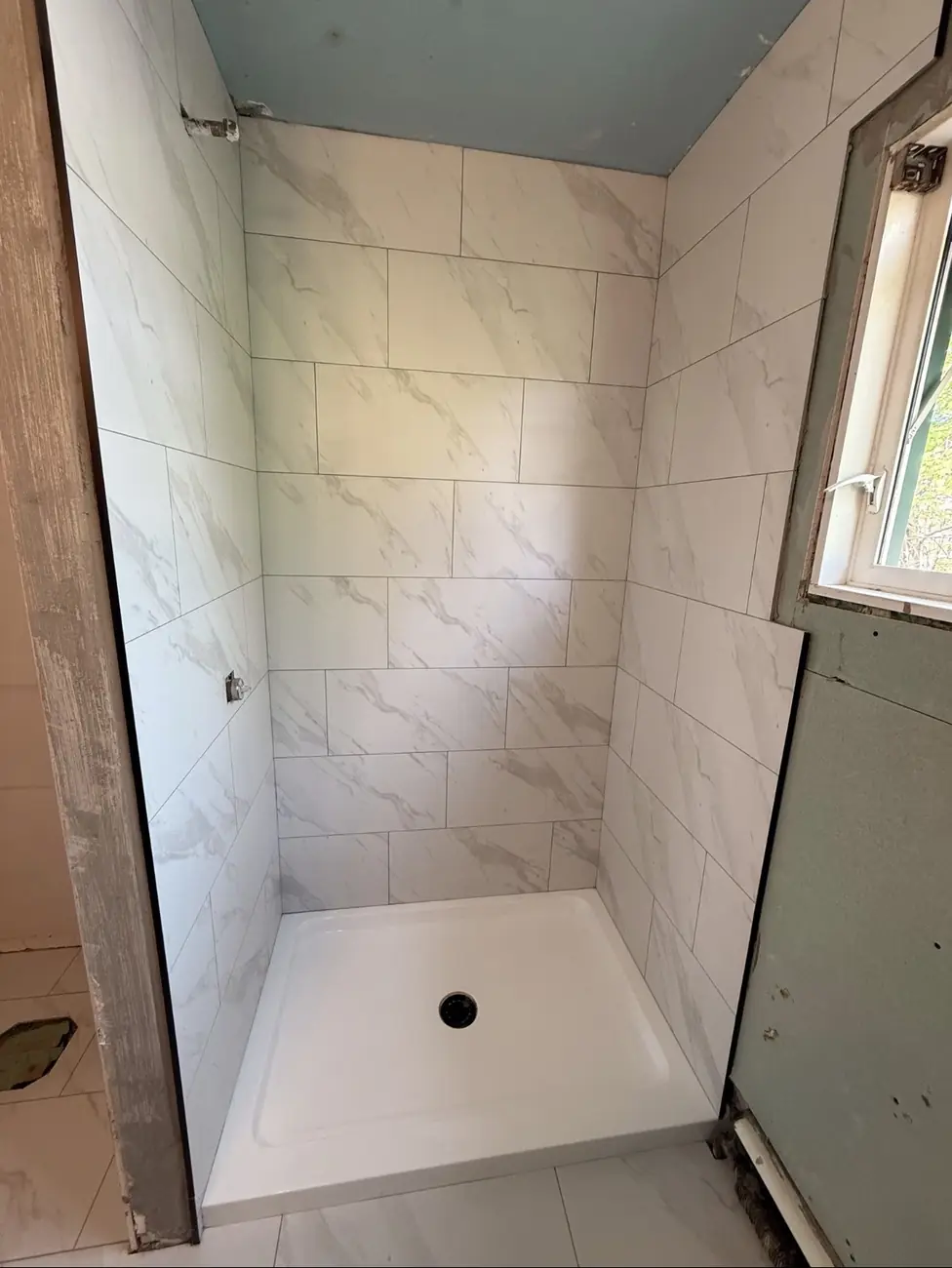 Calgary shower re-tiled in marble-look porcelain with new base after a failed installation by another contractor