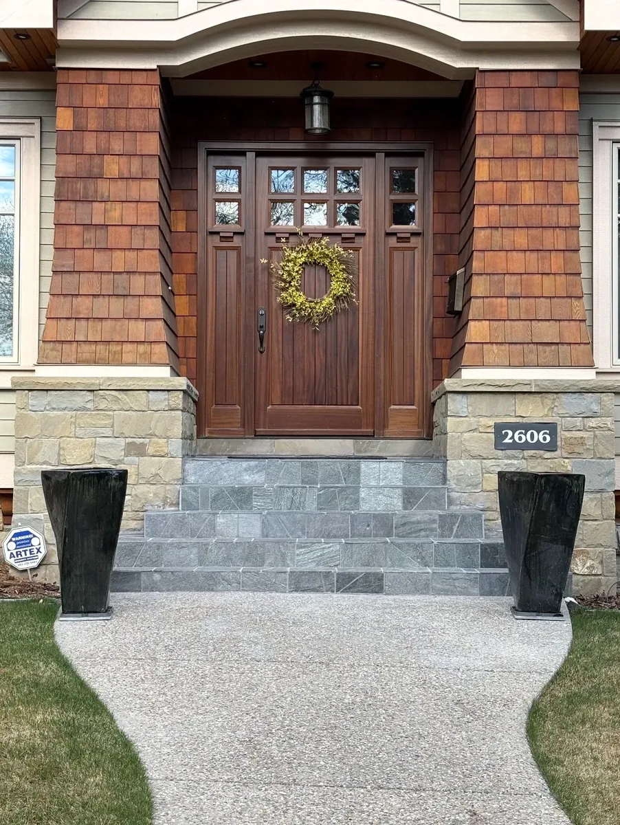 Calgary front-stair slate after renovation — fresh cut light-grey slate treads and risers, clean modern finish framed by stone veneer