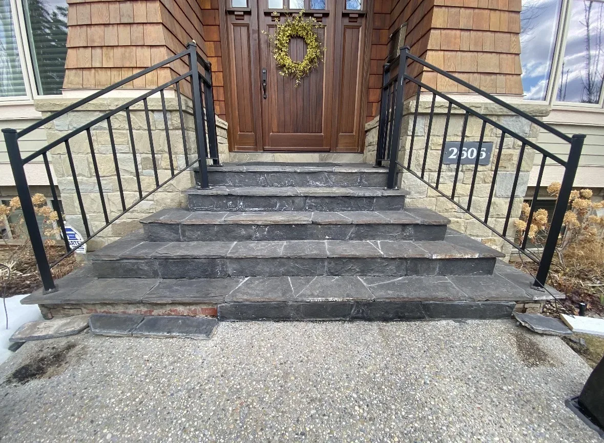 Calgary front-stair slate before renovation — dated dark slate treads and risers, weathered finish, black railings