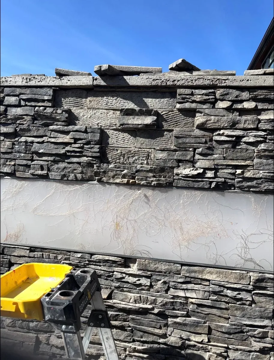 Calgary stone wall before repair — missing stones along the wall, fibre-mesh substrate exposed in the bare strip