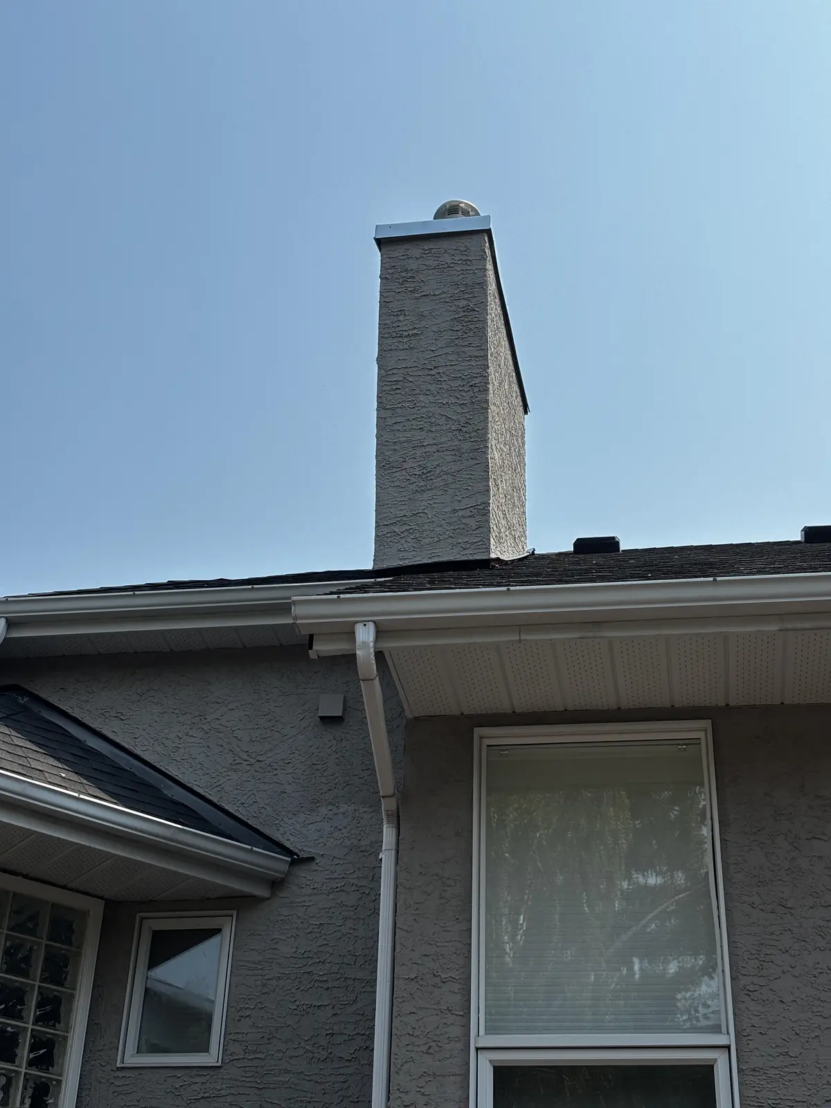 Stucco chimney chase on a Calgary home after repair, new cap and finish matched to the house