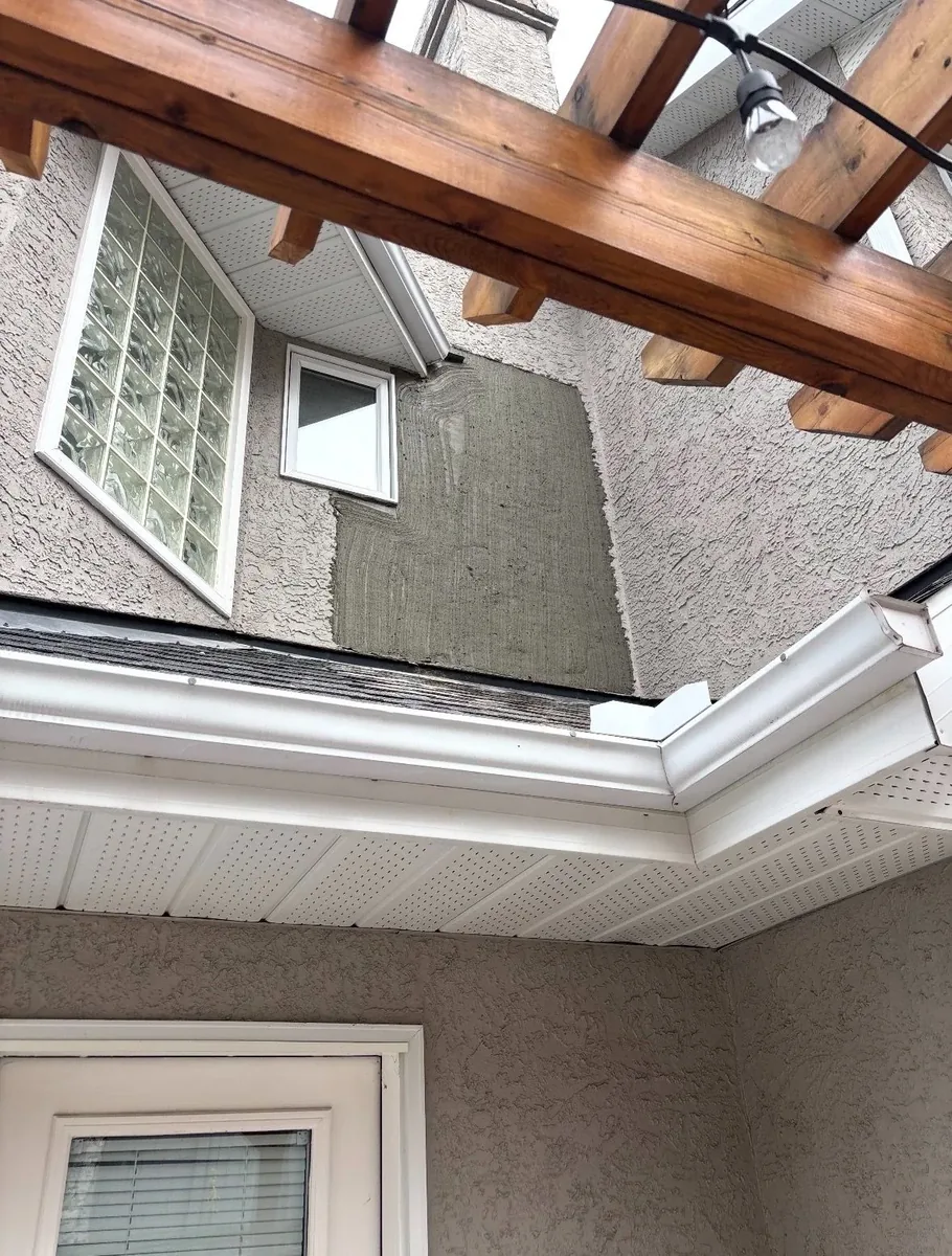 Calgary stucco eave corner after repair — fresh stucco patch applied, texture-matched and weather-tight