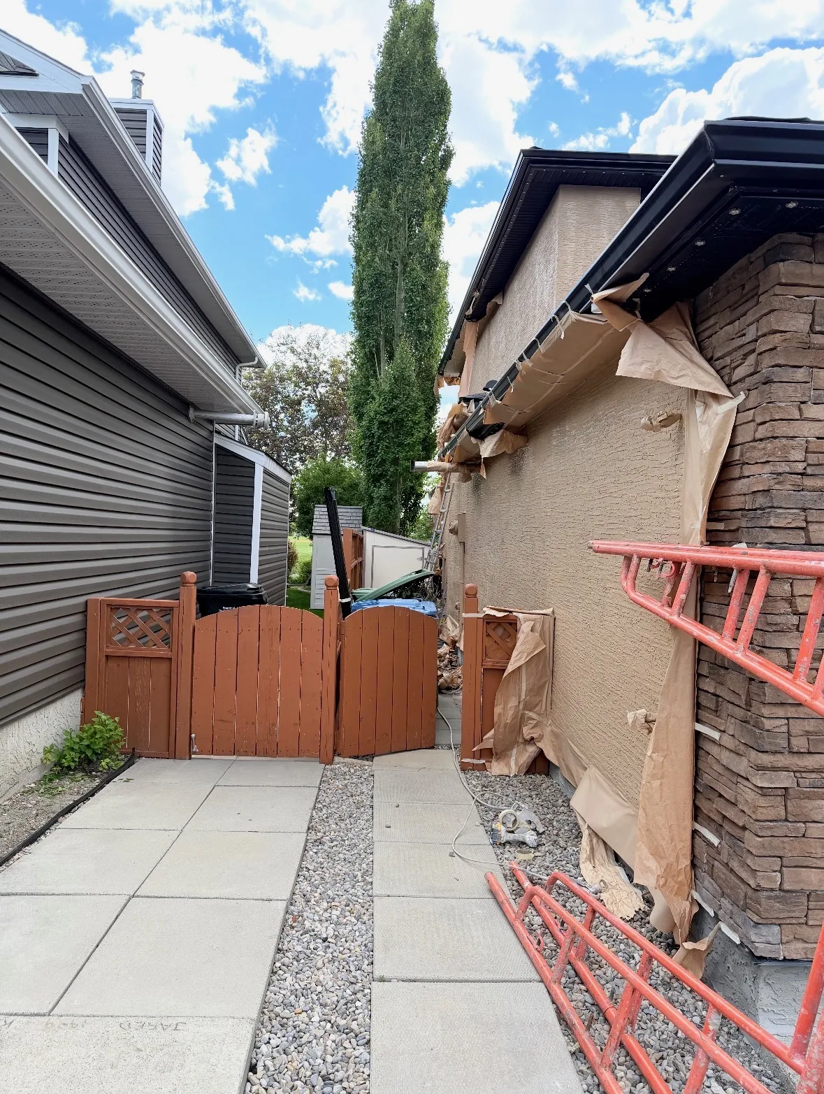 Side elevation of a Calgary house masked with paper and the stone column protected before painting, stucco painting, Calgary