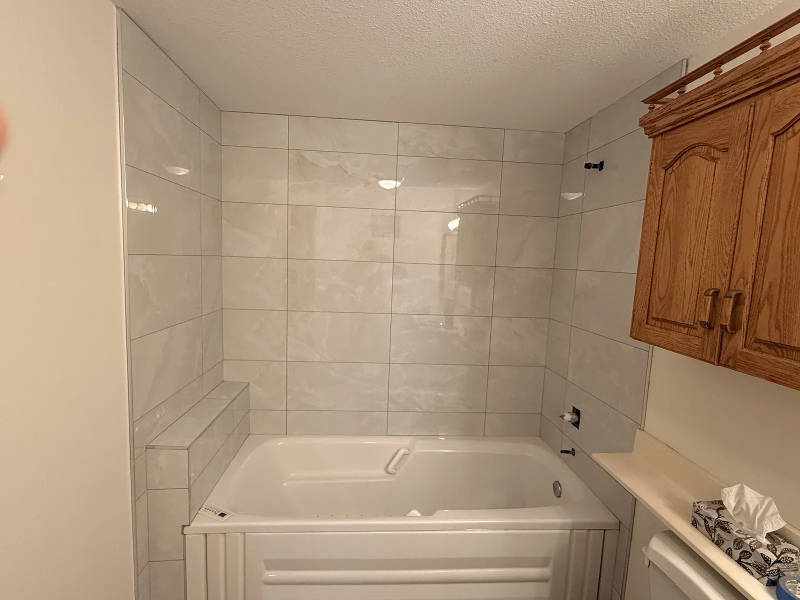 Tub surround in a Calgary bathroom retiled in large-format porcelain with a shampoo shelf