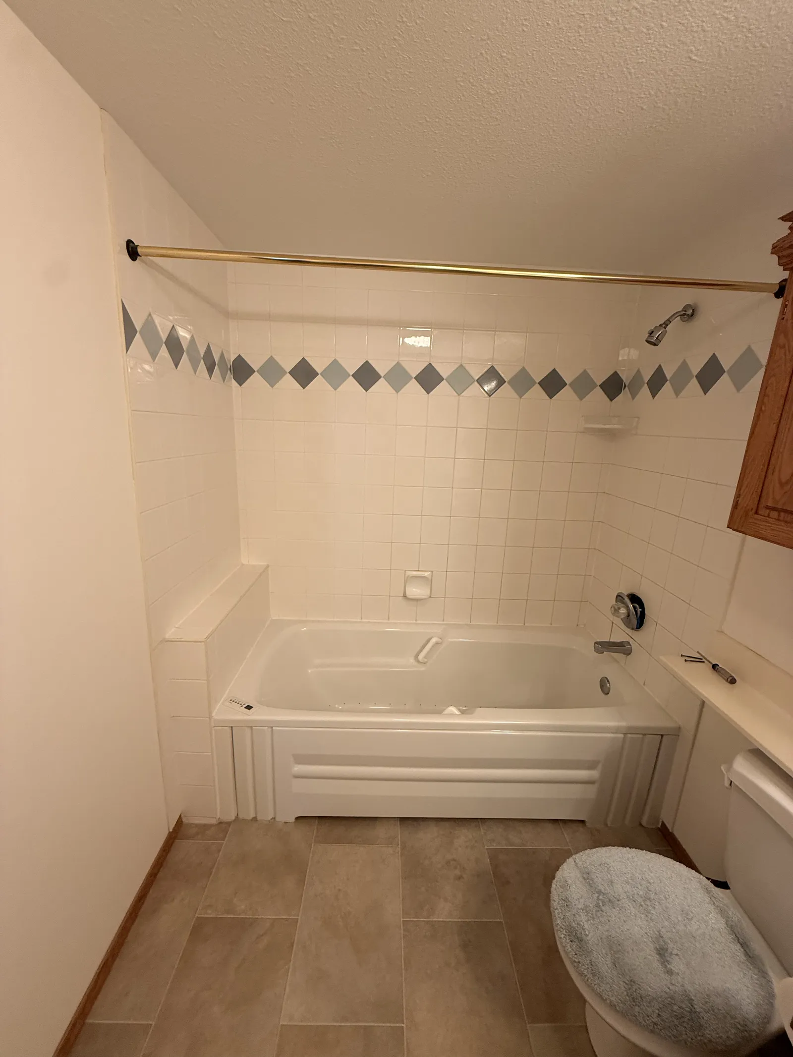 The same Calgary tub surround before, small white tile with a diamond border