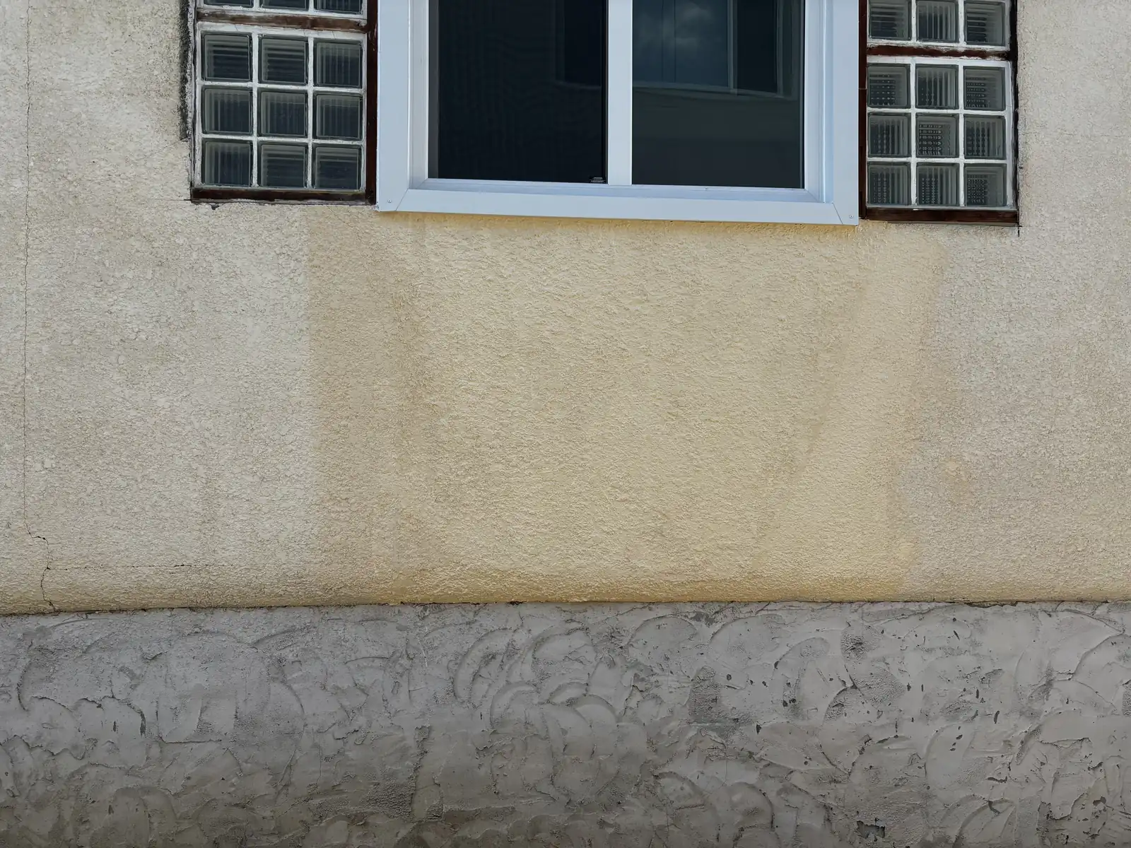 Calgary stucco leak repair below a window completed, wall refinished with a colour-matched texture coat